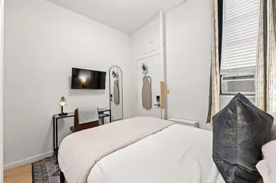 a white bedroom with a bed and a desk at Micro Studio Walk to Time Square in New York