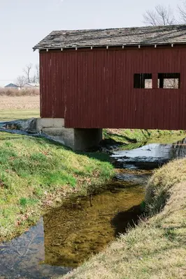 a red bridge over a stream in a field at Beaver Creek Cabin 1 in Strasburg