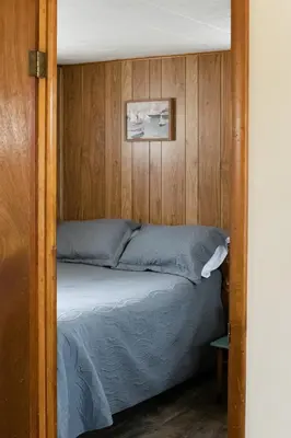 a bed in a room with a wooden wall at Beaver Creek Cabin 5 in Strasburg