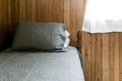 a bed with a gray pillow and a window at Beaver Creek Cabin 5 in Strasburg