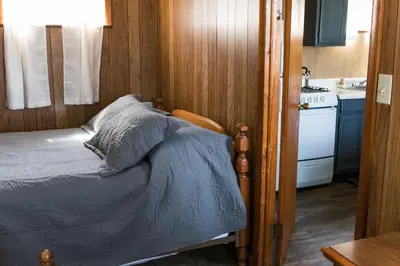 a bedroom with a bed and a kitchen with a stove at Beaver Creek Cabin 6 in Strasburg