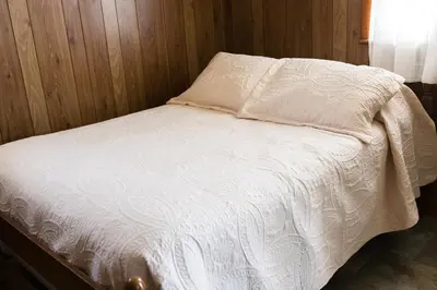 a bed with a white comforter in a room at Beaver Creek Cabin 6 in Strasburg