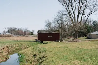 a barn in a field next to a pond at Beaver Creek Cabin 6 in Strasburg