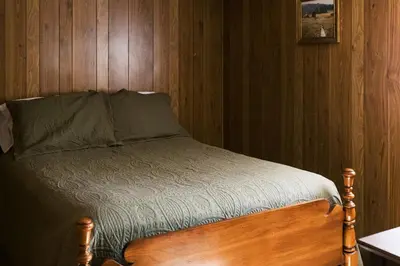 a bed in a room with a wooden wall at Beaver Creek Cabin 2 in Strasburg