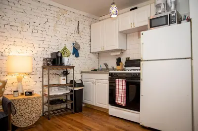 a kitchen with white cabinets and a white refrigerator at Sunny Fully Furnished Studio in Chelsea in New York