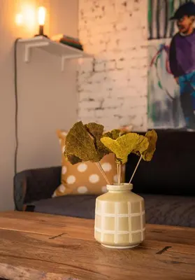 a white vase with flowers on a table at Sunny Fully Furnished Studio in Chelsea in New York