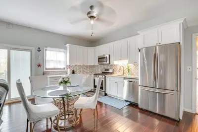 a kitchen with a table and a stainless steel refrigerator at 5 Mi to Rutgers University New Jersey Guest Suite in South River