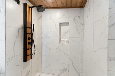 a bathroom with a shower with white marble walls at Perfect Couples Cabin Fireplace Firepit & Wine Nearby in Hawley