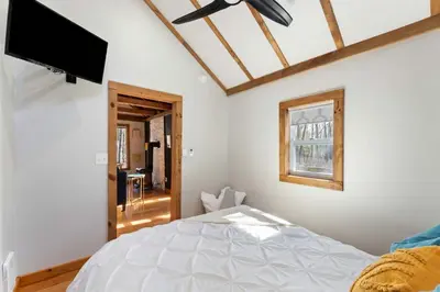 a bedroom with a bed and a flat screen tv at Perfect Couples Cabin Fireplace Firepit & Wine Nearby in Hawley