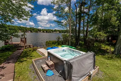 a hot tub on the side of a lake at Water Front Dream Hot Tub Fire Pit King Bed in Tobyhanna