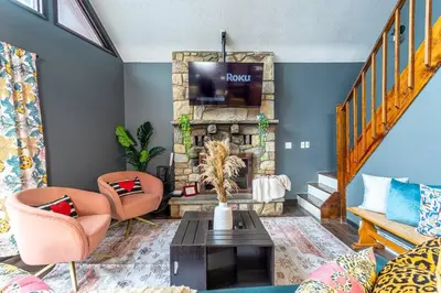 a living room with a stone fireplace with a tv at Water Front Dream Hot Tub Fire Pit King Bed in Tobyhanna