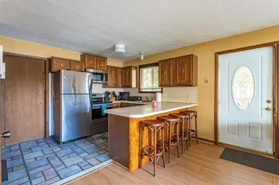 a kitchen with wooden cabinets and a stainless steel refrigerator at Boardwalk Chalet Lakefront Fire Pit Pet Frie in Tobyhanna