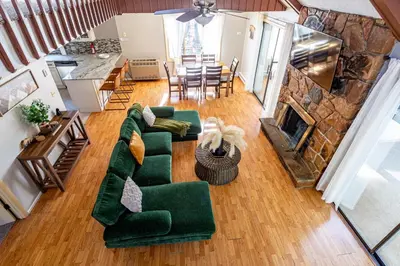 a living room with a green couch and a fireplace at Game Room Fire Pit Dog Friendly in Tobyhanna