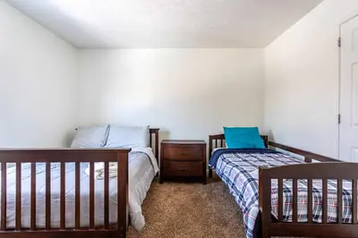 a bedroom with two beds and a dresser and a crib at Lakeside Haven 5 BDR Fire Pit Pet Friendly in Tobyhanna