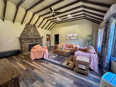 a living room with couches and a stone fireplace at Heated Indoor Private Pool Stream Front Game Room in Cresco