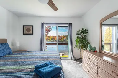 a bedroom with a bed and a large window at Lakeside Chalet 3BR Fire Pit Pet Friendly in Tobyhanna
