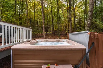 a jacuzzi tub sitting on a deck with trees at Hot Tub Secluded Fire Pit Hammock in Stroudsburg