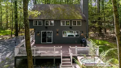 a house with a wrap around porch in the woods at Hot Tub Secluded Fire Pit Hammock in Stroudsburg