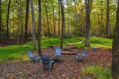 four chairs and a table in the woods at Hot Tub Secluded Fire Pit Hammock in Stroudsburg