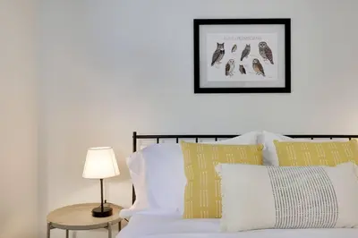 a bed with white pillows and a picture on the wall at Cozy 3 BR Game Area Fire Pit in East Stroudsburg