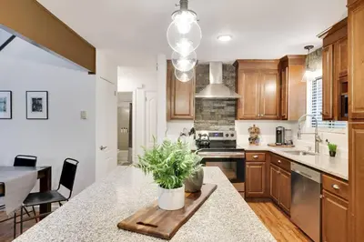 a kitchen with wooden cabinets and a table with a potted plant at Cozy 3 BR Game Area Fire Pit in East Stroudsburg