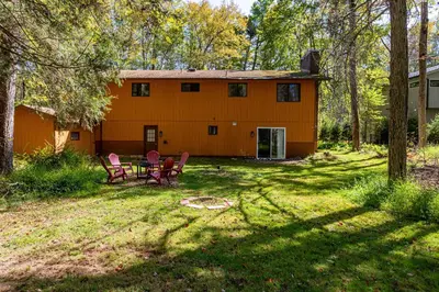 an orange house with chairs and a table in the yard at Serenity Grove Game Room Fire Pit Dog Friend in Pocono Pines