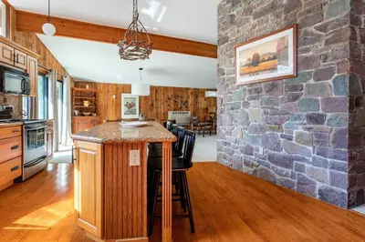a kitchen with a stone wall and a bar at Whispering Pines Chalet Game Room Fire Pit in Pocono Pines