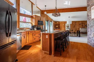 a kitchen with wooden cabinets and a island with bar stools at Whispering Pines Chalet Game Room Fire Pit in Pocono Pines