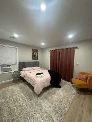 a bedroom with a large bed and a chair at Spacious 6 Bedroom Home with NYC Access & Parking! in Newark