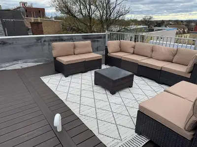 a patio with couches and a coffee table on a roof at Spacious 6 Bedroom Home with NYC Access & Parking! in Newark