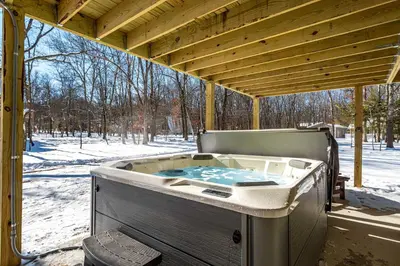 a hot tub sitting under a pavilion in the snow at The Buckhorn Chalet Hot Tub Arcades 6 Bedroom Fire Place in Albrightsville