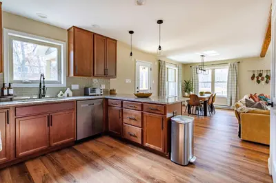 a kitchen with wooden cabinets and a living room at The Buckhorn Chalet Hot Tub Arcades 6 Bedroom Fire Place in Albrightsville