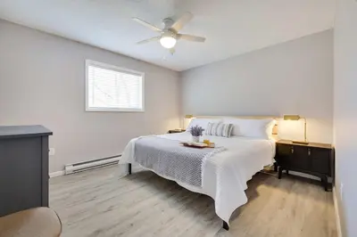 a white bedroom with a bed and a ceiling fan at Blue Wolf Retreat Pool Table Cozy BBQ in Albrightsville