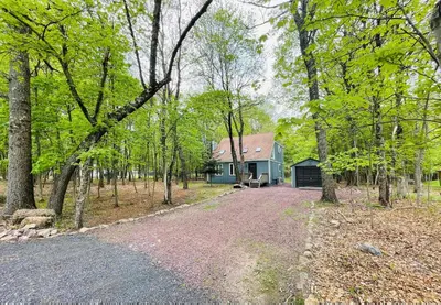 a blue house in the middle of a forest at Blue Wolf Retreat Pool Table Cozy BBQ in Albrightsville
