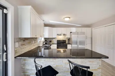a kitchen with white cabinets and black counter tops at Blue Wolf Retreat Pool Table Cozy BBQ in Albrightsville