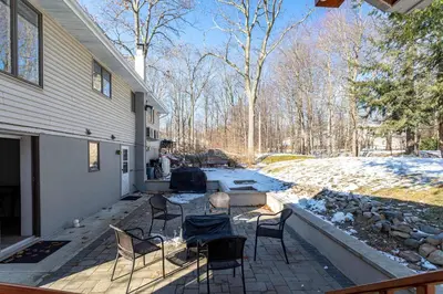 a patio with chairs and a firepit next to a house at The Woodland Escape Pool Table Fire Pit 4 BD in Tobyhanna