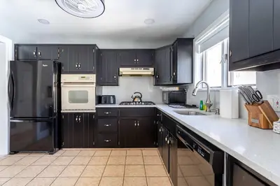a kitchen with black cabinets and a black refrigerator at The Woodland Escape Pool Table Fire Pit 4 BD in Tobyhanna