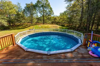 a pool on a wooden deck with a playground at Cedar Cove Retreat Pool BBQ Game Room in Albrightsville