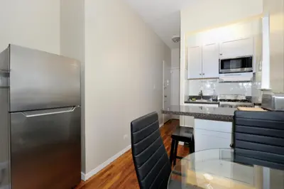 a kitchen with a glass table and a stainless steel refrigerator at Charming 1BR in Murray Hill Kips Bay - Perfect for 2 in New York