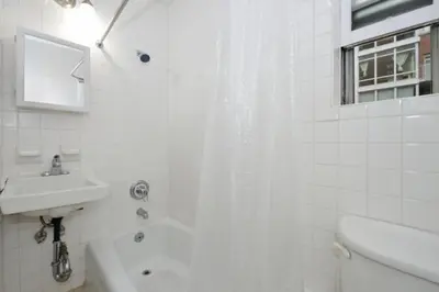 a white bathroom with a shower and a sink at Charming 1BR in Murray Hill Kips Bay - Perfect for 2 in New York