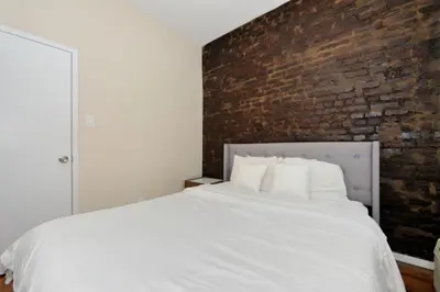 a bedroom with a white bed with a brick wall at Charming 1BR in Murray Hill Kips Bay - Perfect for 2 in New York