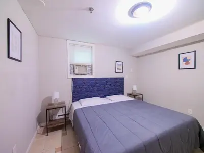 a bedroom with a blue bed with two tables and a window at Spacious 2BR Apartment in Jersey City - Easy NYC Access in Jersey City