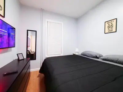 a bedroom with a black bed and a window at NYC Views & Comfort - Modern 2-Bedroom Apartment in Jersey City