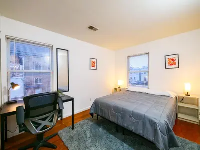 a bedroom with a bed and a desk and two windows at Spacious Apt near NYC 7BR Family-Friendly & Modern Amenities in Jersey City