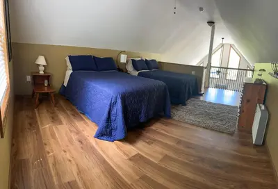 a bedroom with two beds with blue sheets and a wooden floor at Wallenpaupack Lake house in Greentown