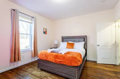 a bedroom with a bed with an orange blanket at Family Apt: 2BR FREE Parking Airprt City Links in Newark