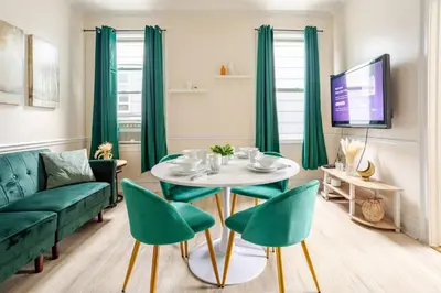 a living room with a table and green chairs at 6-Guest Jersey City Haven: Location-Comfort-Vibes in Jersey City