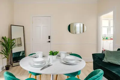 a dining room with a white table and green chairs at 6-Guest Jersey City Haven: Location-Comfort-Vibes in Jersey City