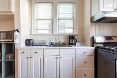 a kitchen with white cabinets and a sink at City Outside Serenity Inside: 2B1B NYC - 40 Min in Jersey City