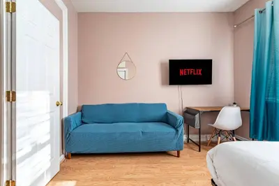 a living room with a blue couch and a television at City Outside Serenity Inside: 2B1B NYC - 40 Min in Jersey City